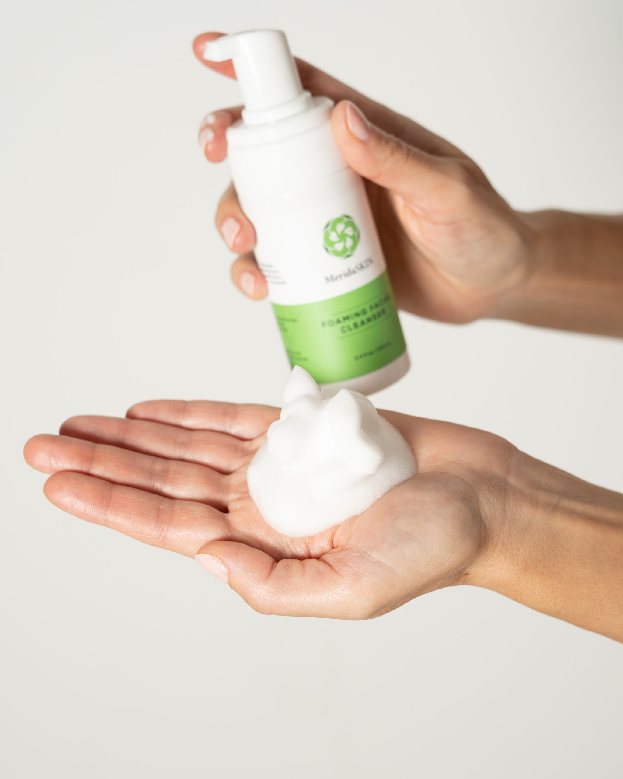 Close-up of foaming facial cleanser dispensed into palm